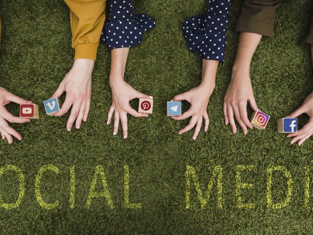 overhead-view-female-s-hand-holding-social-network-app-symbol-blocks-lawn